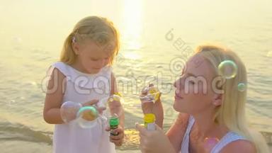 快乐的家庭在美丽的夕阳下，在海滩上玩<strong>泡泡泡泡</strong>，在慢动作中度过快乐的假期